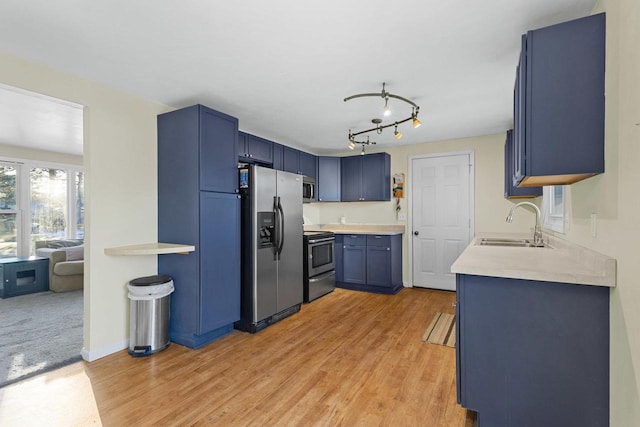 kitchen featuring stainless steel appliances, blue cabinets, sink, and light hardwood / wood-style floors