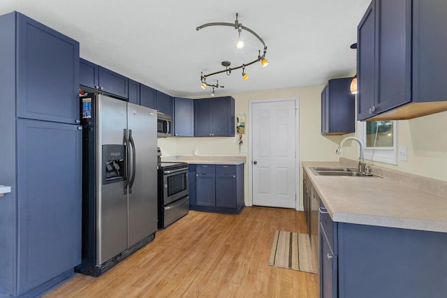 kitchen with stainless steel appliances, light wood-type flooring, blue cabinetry, and sink