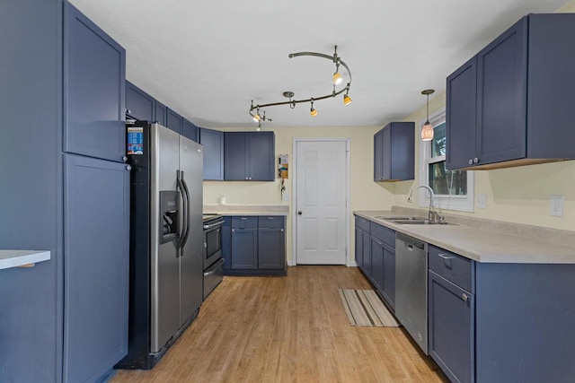 kitchen with sink, blue cabinetry, hanging light fixtures, and appliances with stainless steel finishes