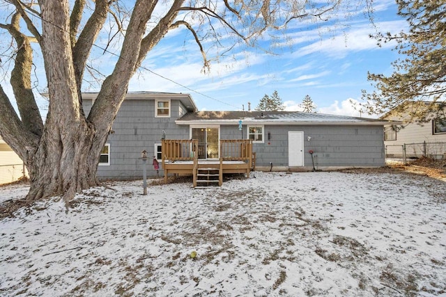 snow covered back of property featuring a deck