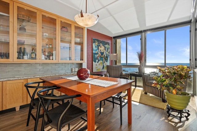 dining space featuring dark hardwood / wood-style flooring, floor to ceiling windows, and a water view