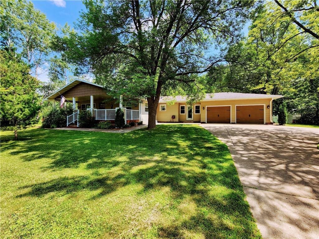 single story home with a porch, a front yard, and a garage