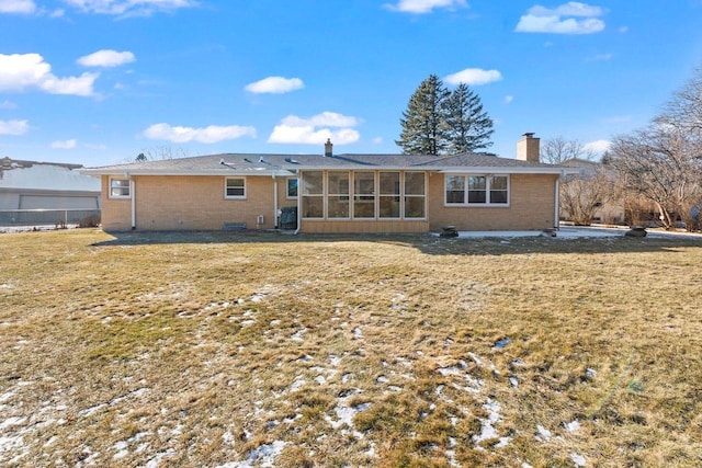 rear view of property featuring central AC unit, a lawn, and a sunroom