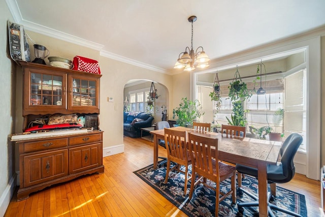 dining space with light hardwood / wood-style flooring, crown molding, and a chandelier