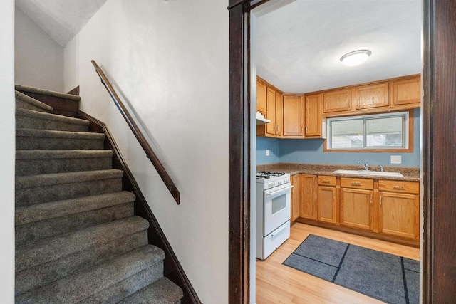 kitchen featuring white range with gas stovetop, light hardwood / wood-style flooring, and sink