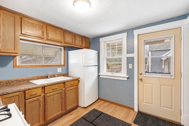 kitchen with white fridge, light hardwood / wood-style flooring, and sink