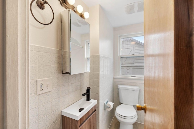 bathroom featuring tile walls, vanity, and toilet