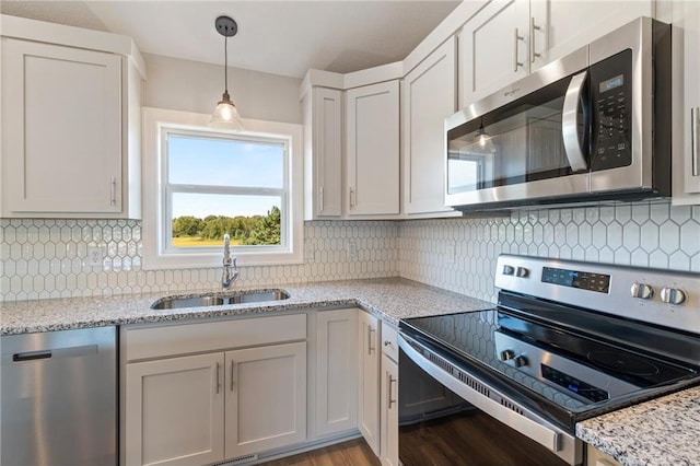 kitchen with sink, white cabinetry, light stone counters, and appliances with stainless steel finishes