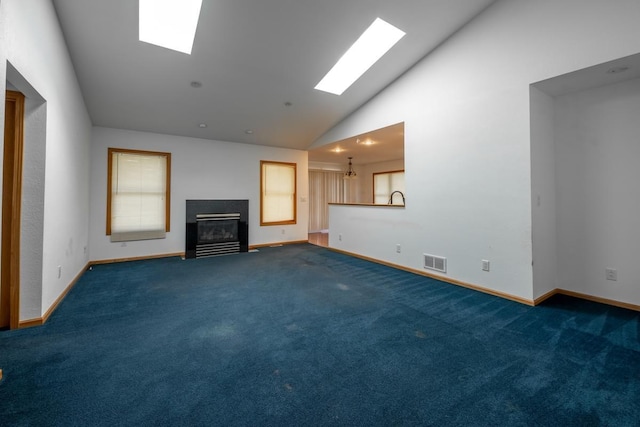 unfurnished living room with high vaulted ceiling, carpet floors, and a skylight