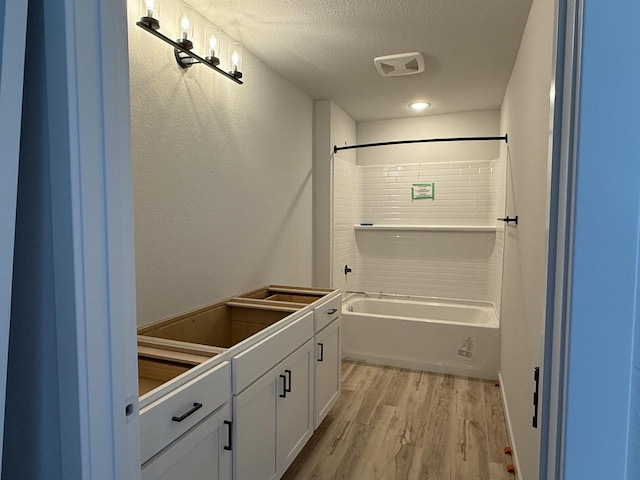 bathroom with a textured ceiling, shower / bathing tub combination, and hardwood / wood-style floors