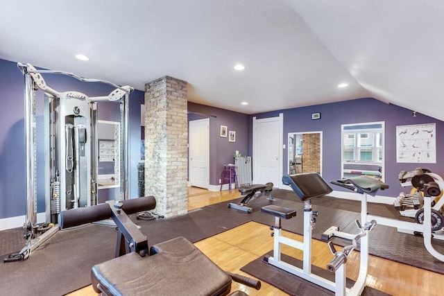 exercise room with decorative columns and lofted ceiling