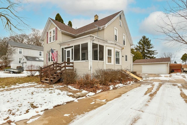 view of front of home featuring an outdoor structure, a garage, and a sunroom