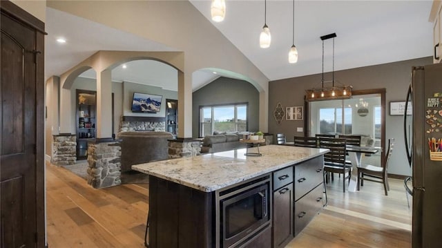 E5695 510th Ave, Menomonie, WI 54751 - kitchen with stainless steel microwave, hanging light fixtures, black fridge, a kitchen island, and lofted ceiling