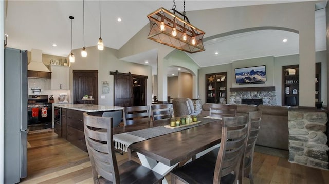 E5695 510th Ave, Menomonie, WI 54751 - dining space with a fireplace, vaulted ceiling, a barn door, and light hardwood / wood-style flooring