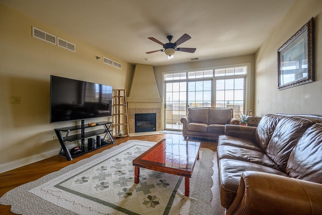 living room featuring hardwood / wood-style flooring, ceiling fan, and a fireplace