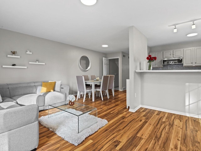 living room featuring rail lighting and dark hardwood / wood-style flooring