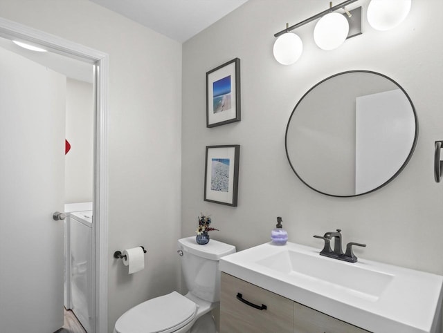 bathroom with toilet, washer and dryer, and vanity