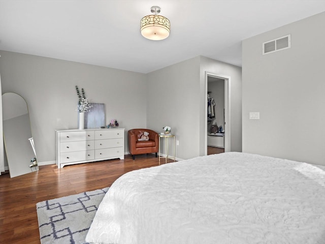 bedroom with dark wood-type flooring, a walk in closet, and a closet