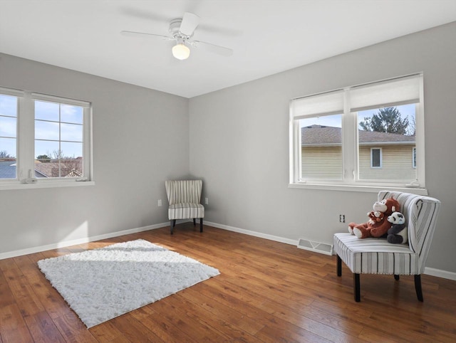 living area with wood-type flooring and ceiling fan