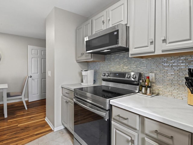 kitchen with appliances with stainless steel finishes, tasteful backsplash, and white cabinetry