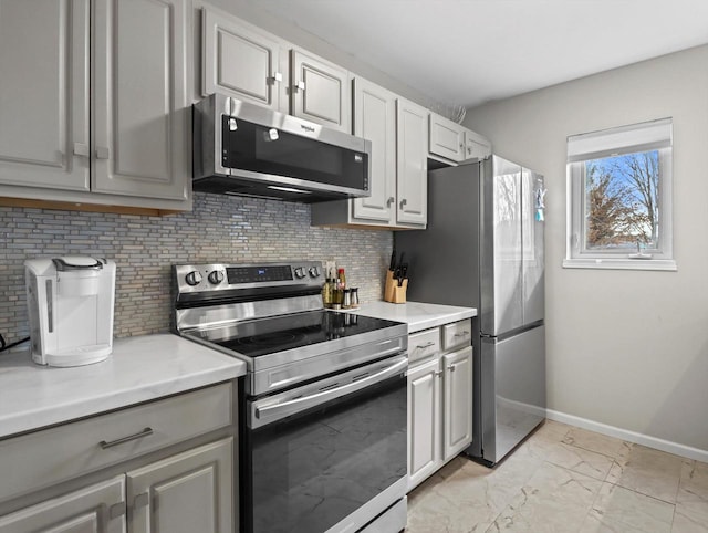 kitchen featuring stainless steel appliances, backsplash, and gray cabinets