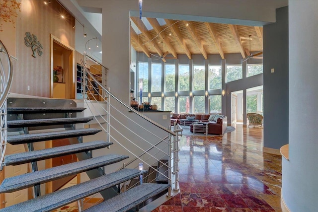 staircase featuring beam ceiling, wood ceiling, and a high ceiling