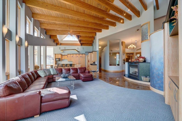 living room with a towering ceiling, a chandelier, carpet flooring, and beamed ceiling