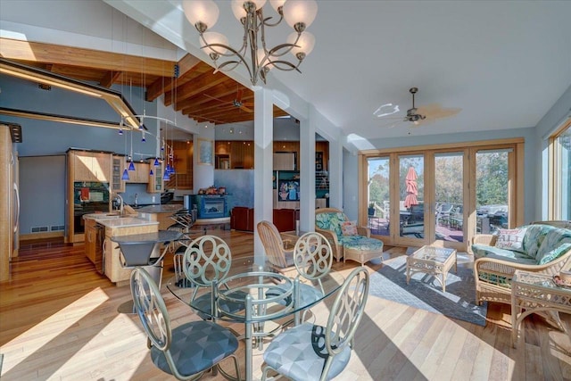 dining room featuring ceiling fan with notable chandelier, french doors, light wood-type flooring, and beamed ceiling