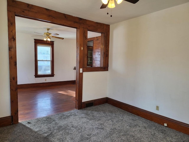 spare room with ceiling fan and dark colored carpet