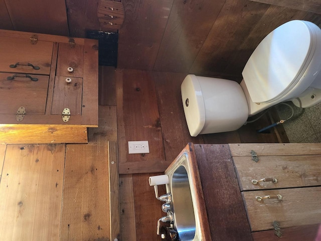 bathroom with wood ceiling, wood walls, and toilet