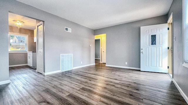 empty room with an inviting chandelier and dark wood-type flooring