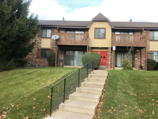 view of property featuring a balcony and a front lawn