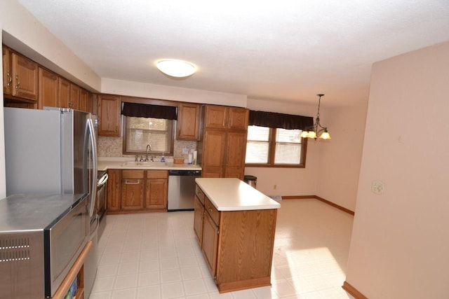 kitchen with pendant lighting, stainless steel appliances, a notable chandelier, a kitchen island, and sink