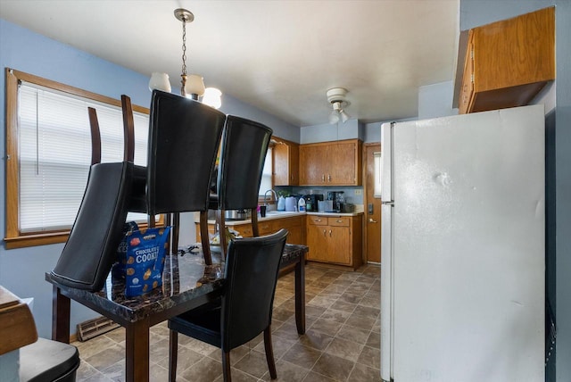 kitchen featuring a wealth of natural light, a chandelier, white fridge, pendant lighting, and sink