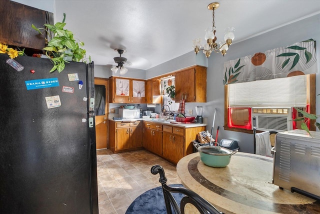 kitchen with ceiling fan with notable chandelier, pendant lighting, black refrigerator, and sink