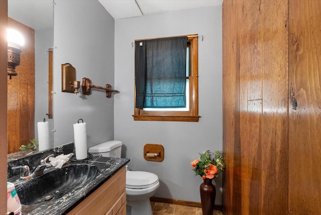 bathroom with toilet, vanity, and tile patterned floors