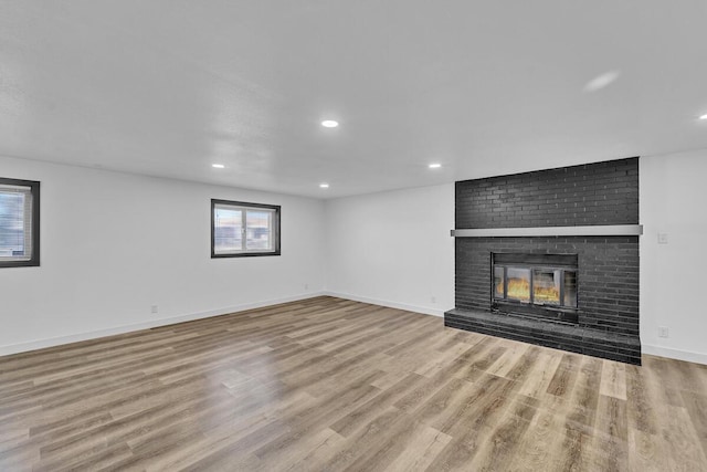 unfurnished living room with a brick fireplace and light hardwood / wood-style floors