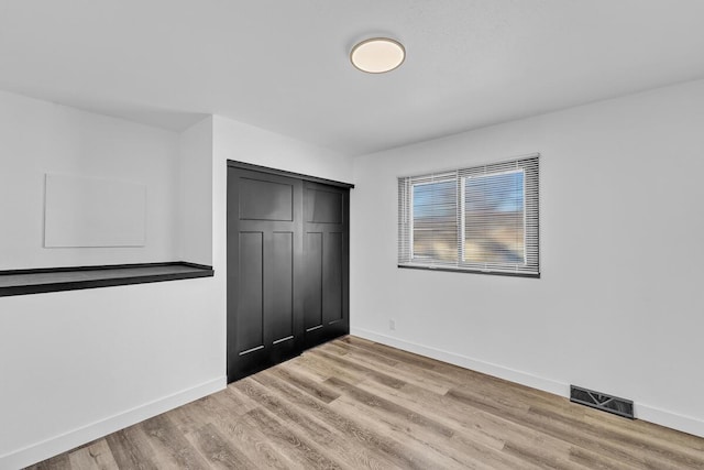 unfurnished bedroom with light wood-type flooring and a closet