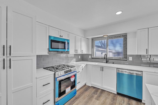 kitchen with hardwood / wood-style floors, white cabinets, appliances with stainless steel finishes, sink, and backsplash