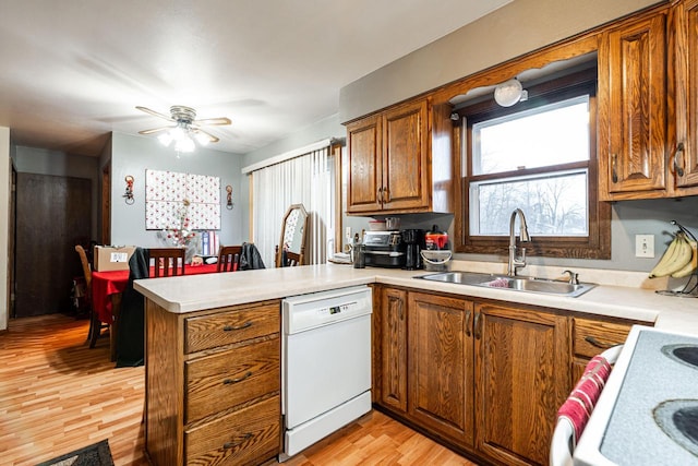 kitchen with dishwasher, kitchen peninsula, ceiling fan, sink, and light hardwood / wood-style flooring