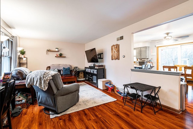 living room featuring ceiling fan and dark wood-type flooring