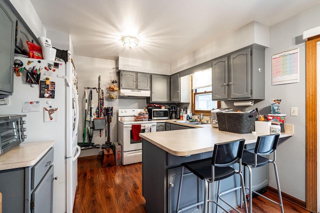 kitchen with sink, white appliances, kitchen peninsula, gray cabinets, and a breakfast bar