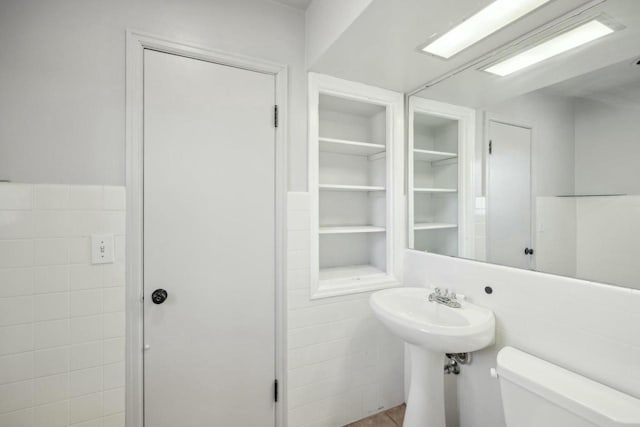 bathroom featuring toilet and tile walls