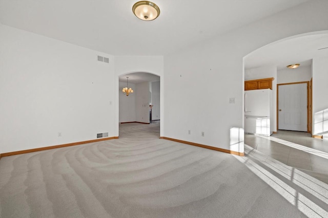 spare room with light carpet and a chandelier