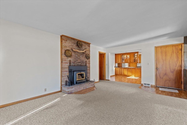 N4621 Lake Dr, Hustisford, WI 53034 - unfurnished living room featuring an inviting chandelier, carpet flooring, and a wood stove