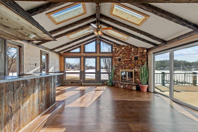 N4621 Lake Dr, Hustisford, WI 53034 - unfurnished living room with hardwood / wood-style flooring, ceiling fan, lofted ceiling with skylight, and a stone fireplace