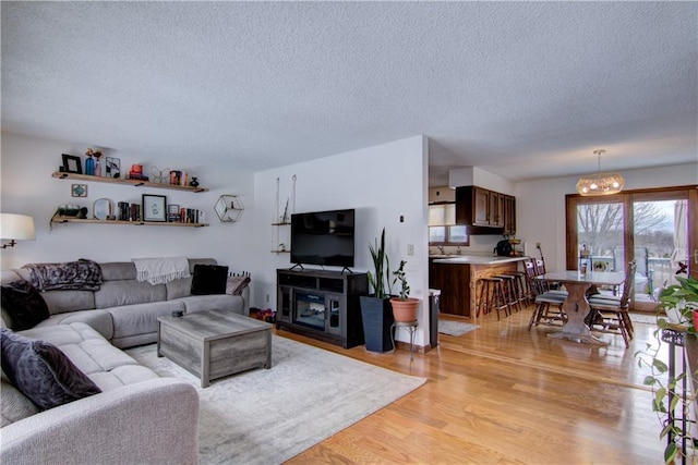 living room with a notable chandelier, a textured ceiling, and light hardwood / wood-style floors