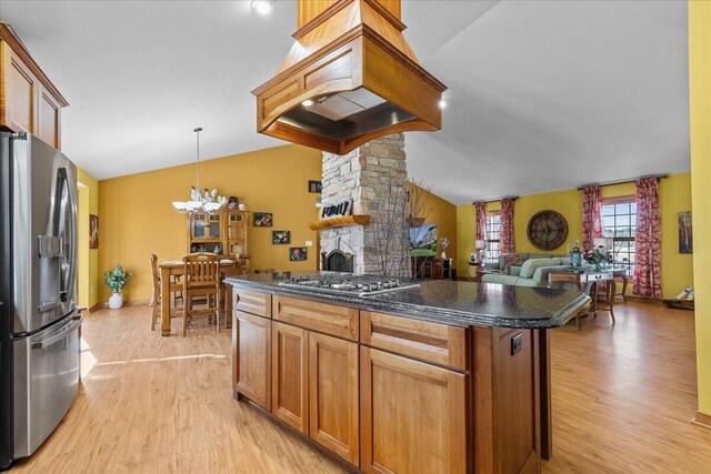 kitchen featuring appliances with stainless steel finishes, custom exhaust hood, hanging light fixtures, vaulted ceiling, and light hardwood / wood-style flooring