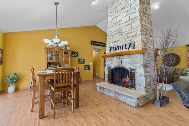 dining area with vaulted ceiling, a fireplace, a chandelier, and hardwood / wood-style flooring