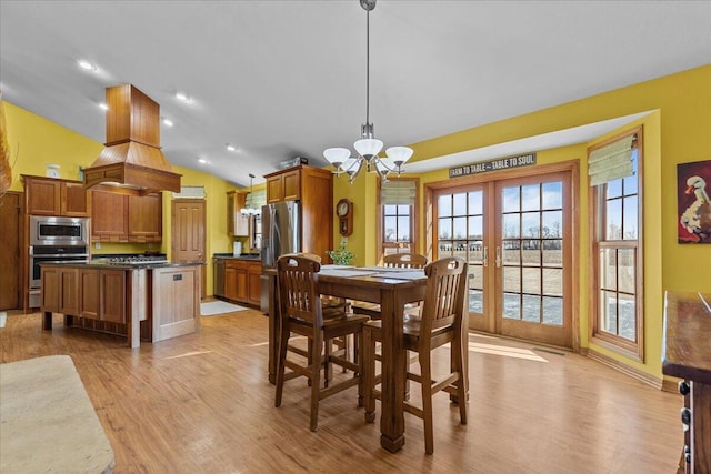 dining room with lofted ceiling, french doors, a chandelier, and light hardwood / wood-style flooring